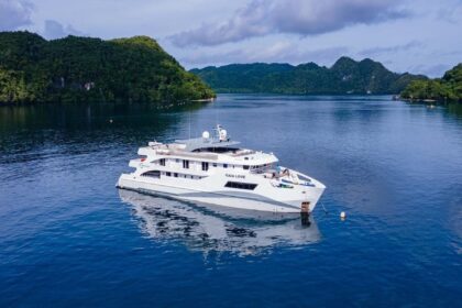 Gaia Love liveaboard yacht anchored in a calm bay surrounded by jungle covered islands