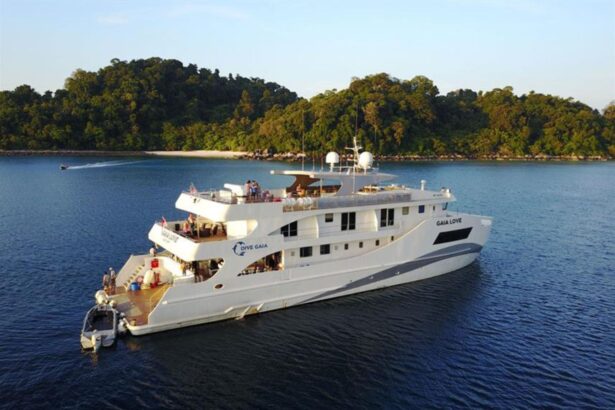 The Gaia Love liveaboard anchored near a forested island at dusk