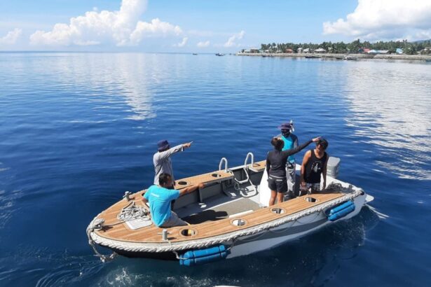 Crew members aboard a tender boat heading toward a coastal village