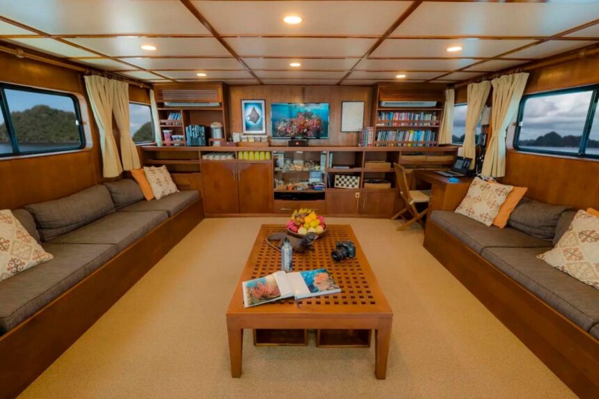 Wood-paneled saloon on the Mermaid II with sofas, bookshelves and a coffee table