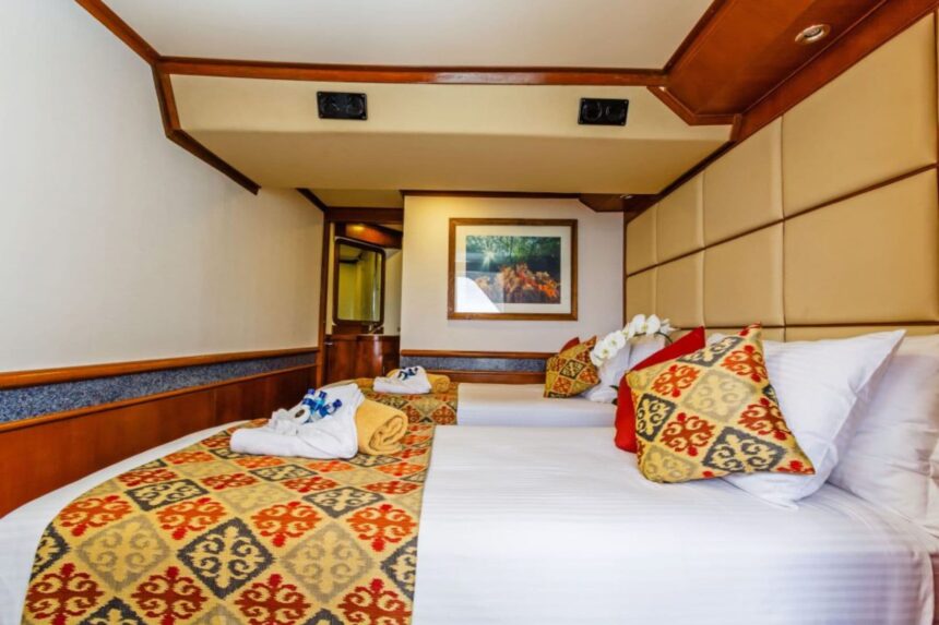 Twin cabin on the Mermaid I with patterned bedding and a framed reef photo
