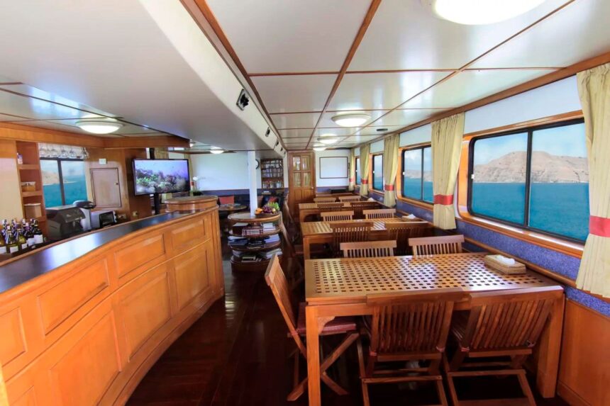 Wood-paneled lounge and bar area on the Mermaid I with dining tables