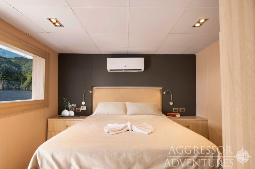 Cabin bed with air conditioning unit and ocean view window aboard the Cocos Island Aggressor