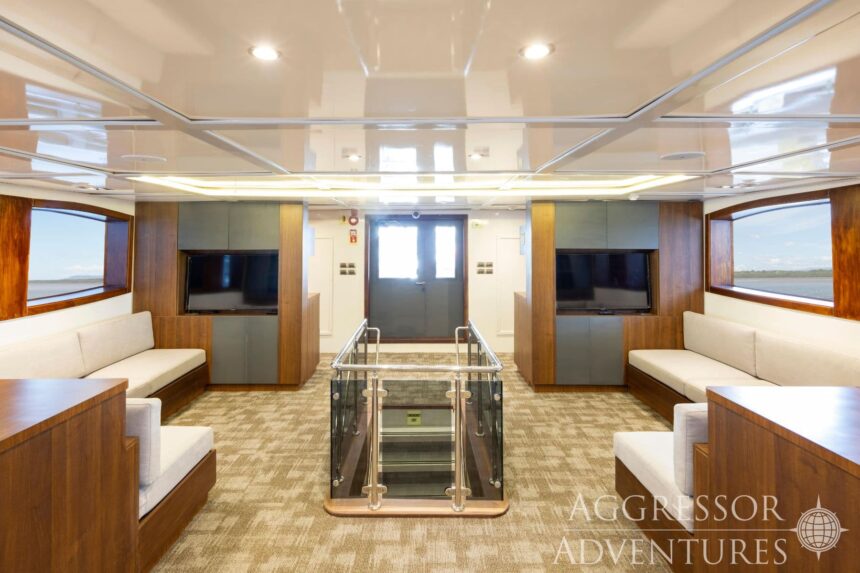 Lounge area with sofas, TVs and a staircase aboard the Cocos Island Aggressor