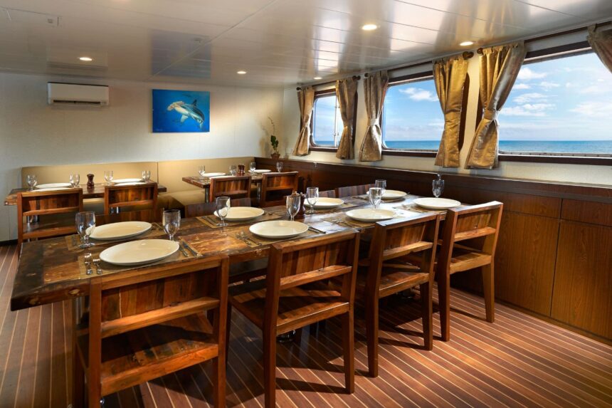Indoor dining room with wooden tables set for a meal and ocean view windows