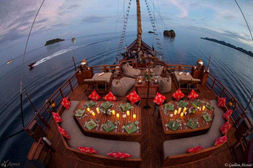 Wide-angle view of the Arenui's dinner tables set on deck at dusk