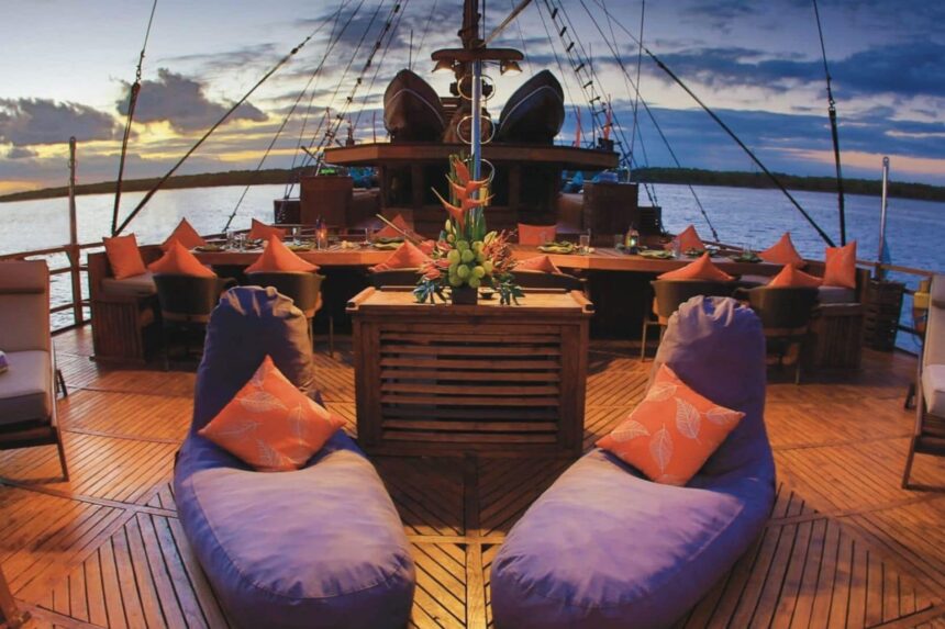 Lounge seating and dining tables on the Arenui's deck at dusk