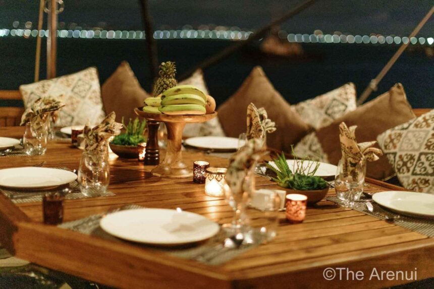 Table set for dinner with a fruit display on the Arenui's deck at night