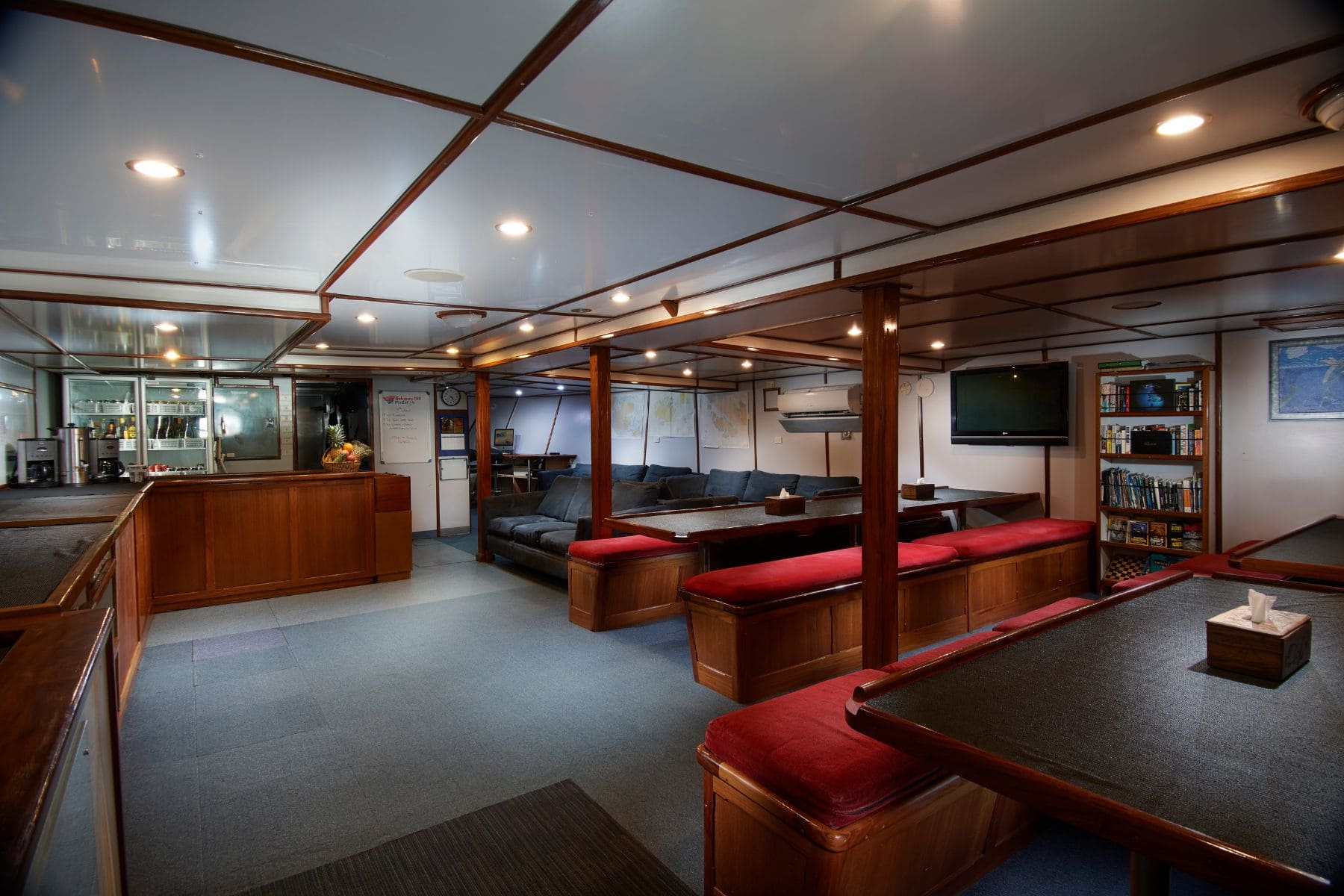 Indoor lounge with couches, bookshelf and TV aboard the Pacific Master
