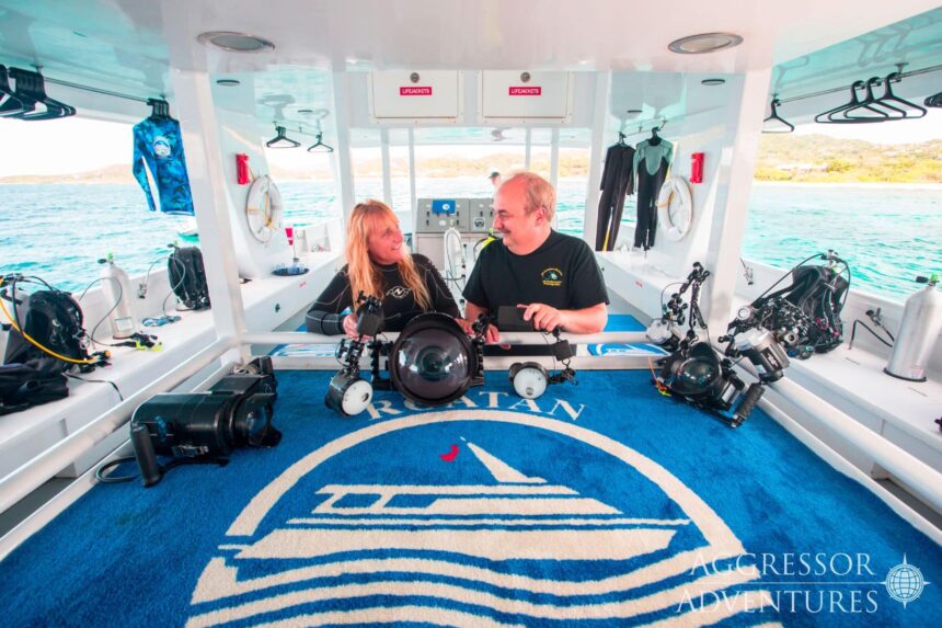 Two divers set up underwater camera housings on the Roatan Aggressor's dive deck