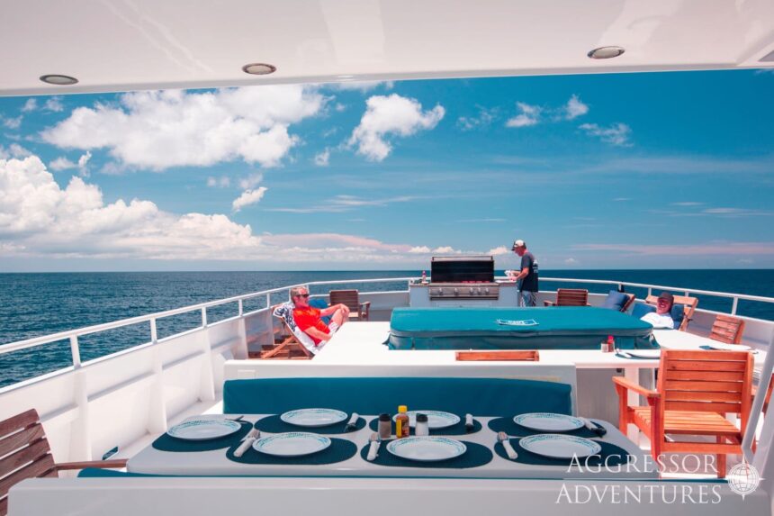 Sun deck of the Roatan Aggressor with loungers, a grill and a set dining table