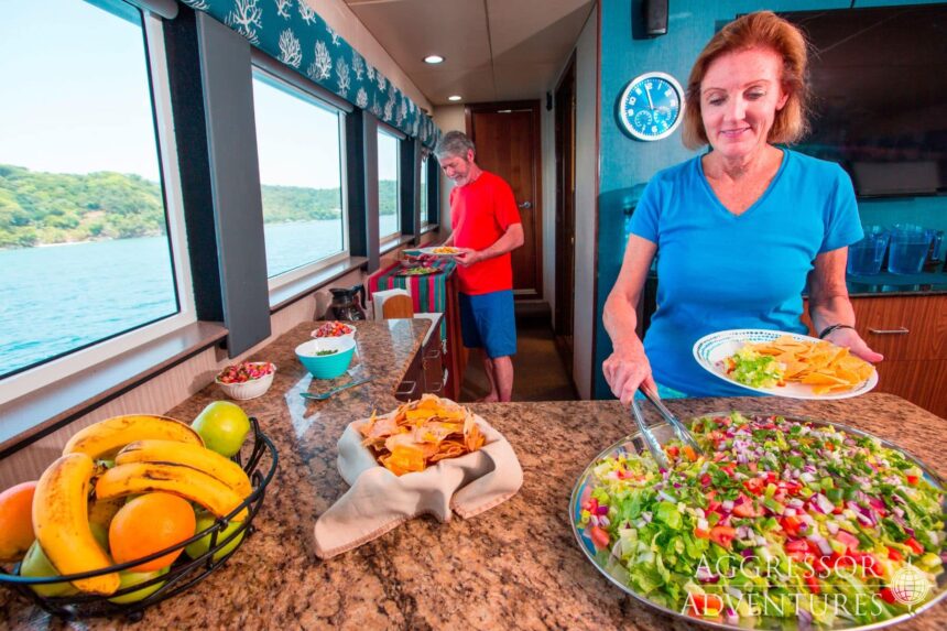 Crew and guests preparing a spread of fruit, chips and salsa in the galley