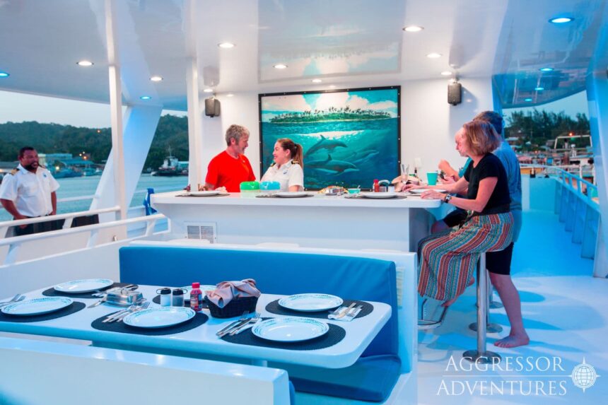 Guests and crew chatting at the bar during dinner service on deck