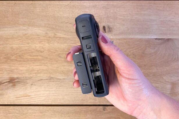 Insta360 X3 held in one hand with the battery and memory card compartment open