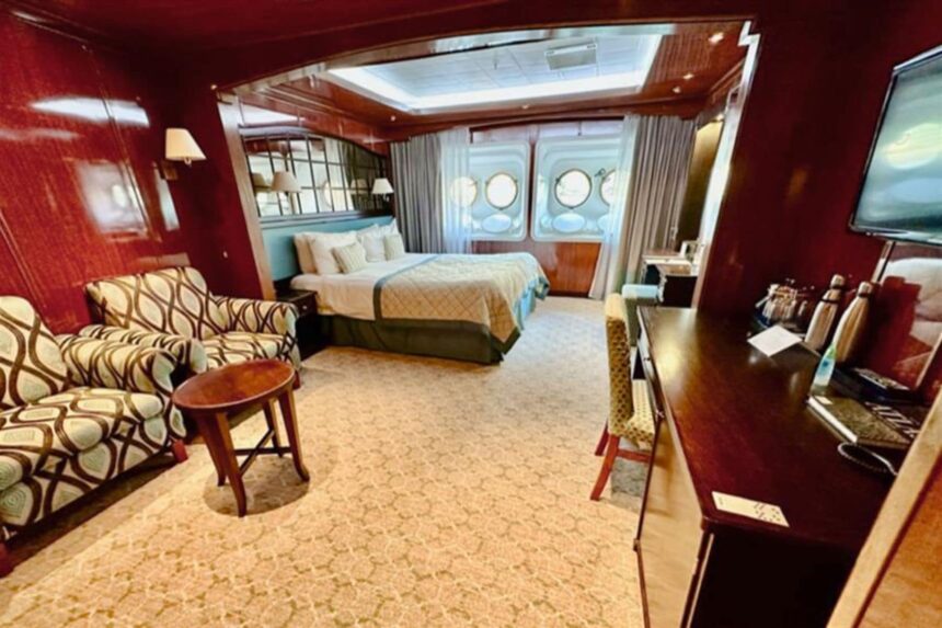 Spacious suite aboard the Caledonian Sky with a large bed and armchairs