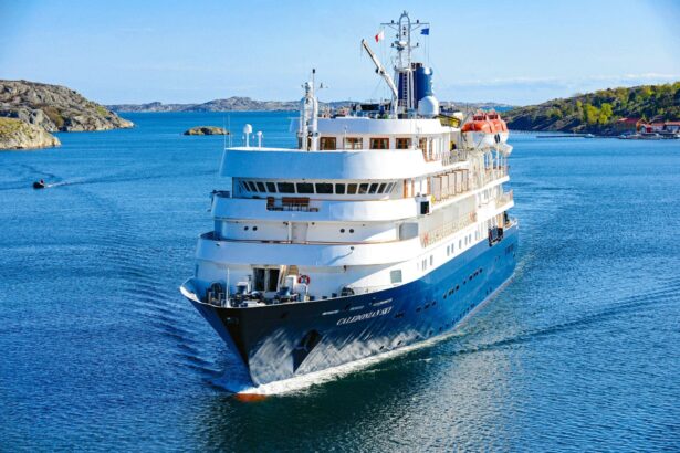 The Caledonian Sky expedition ship cruising past green coastal hills