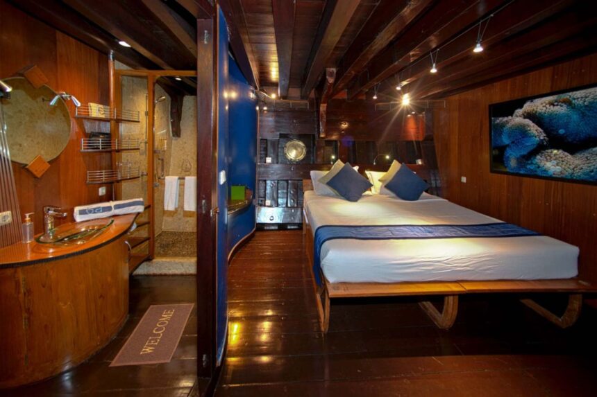 Cabin bed with reef artwork and a welcome mat aboard the Dewi Nusantara