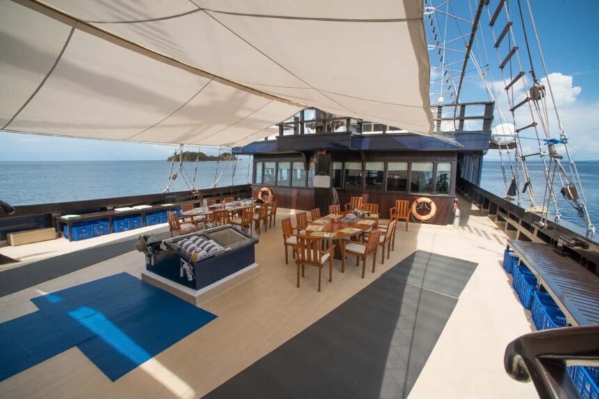 Shaded alfresco dining tables set up on the Dewi Nusantara's rear deck