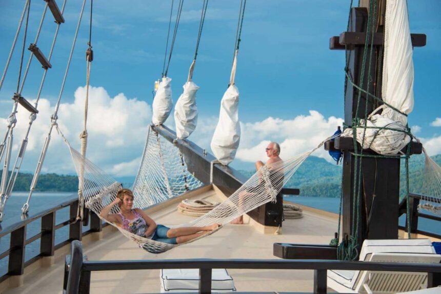 Guests relaxing in rope hammocks strung along the Dewi Nusantara's foredeck rigging