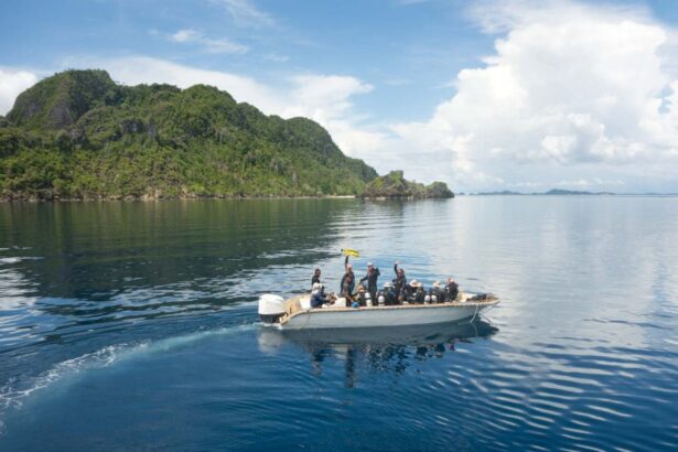 Divers riding a tender boat toward a forested island coastline near the Dewi Nusantara