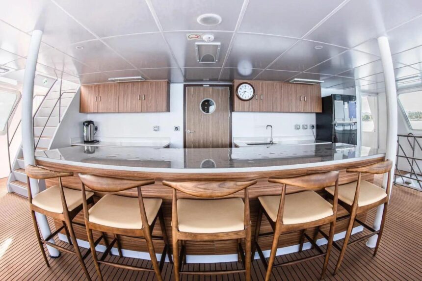 Curved wooden bar counter with stools in the White Manta's galley and dining area