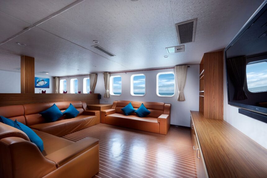 Lounge on the White Manta with leather sofas, blue cushions and a wall-mounted TV