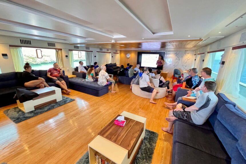 guests attending a dive briefing lecture in the liveaboard lounge