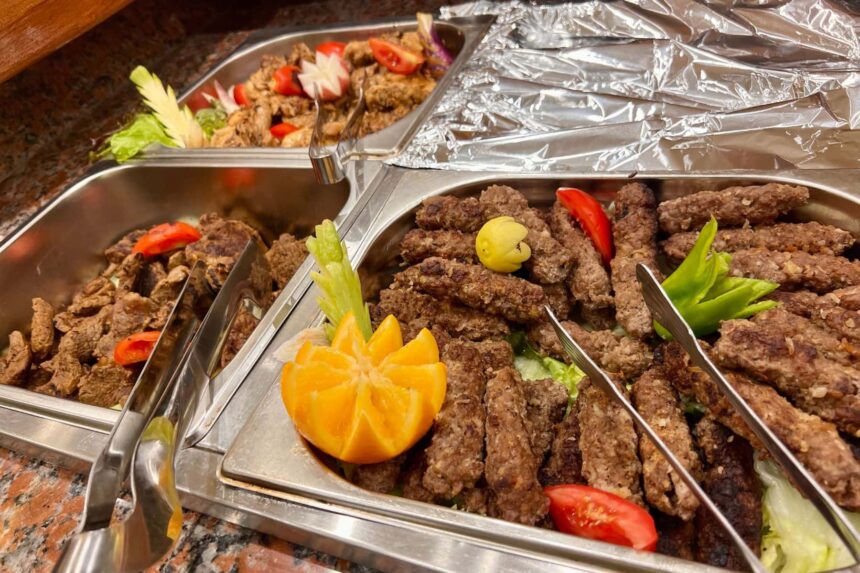 buffet trays of grilled kofta and salad garnished with citrus and vegetables