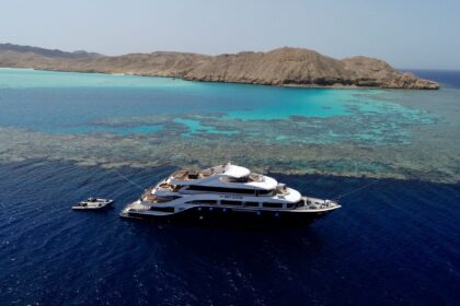 The All Star Red Sea liveaboard Scuba Scene anchored over a reef near desert hills