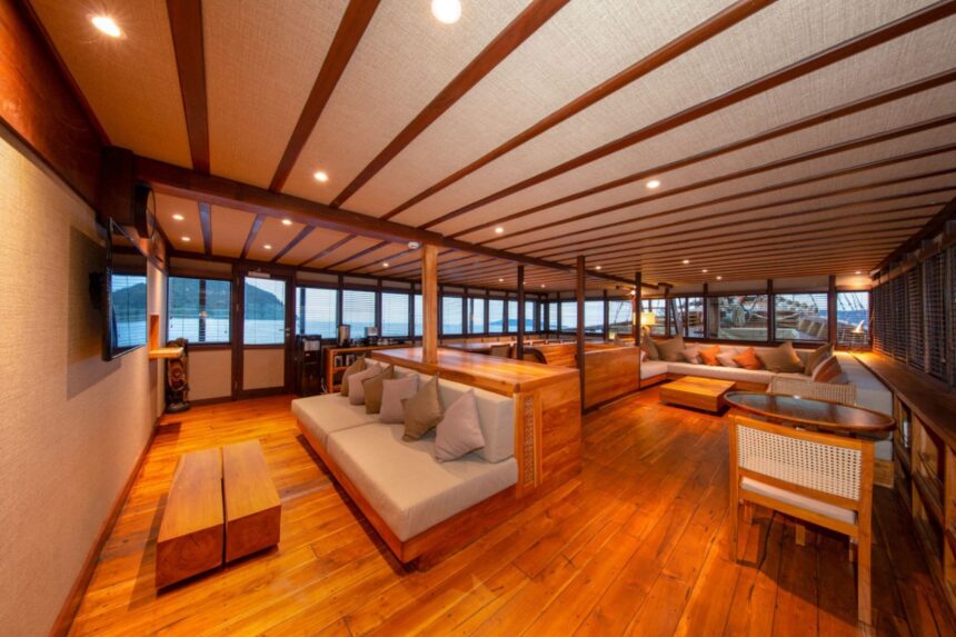 Wood-paneled lounge with sofas and TV aboard the Coralia liveaboard
