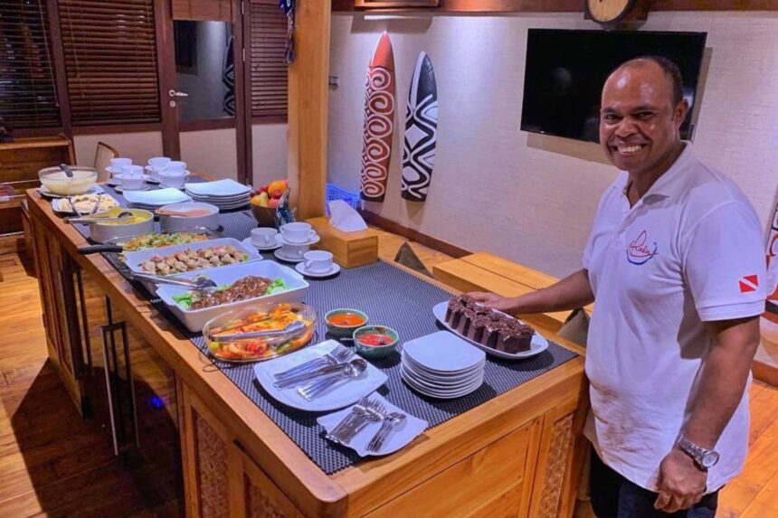 Crew member presenting a dessert cake at the buffet table aboard the Coralia