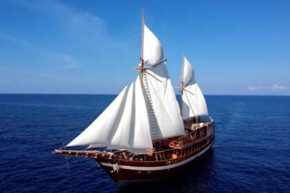 Coralia liveaboard schooner sailing under full white sails on open water