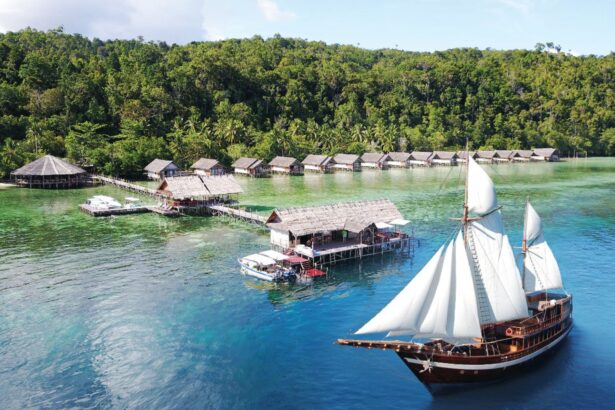 Traditional phinisi schooner anchored near a stilted village and jetty in Indonesia