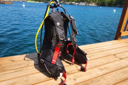 Aqualung Axiom i3+ BCD on a wooden dock, showing its red weight release handles and yellow low pressure hose
