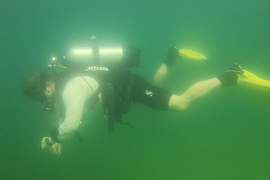 DIVEIN tester finning through green lake water in the SEAC EQ-Pro BCD during a test dive