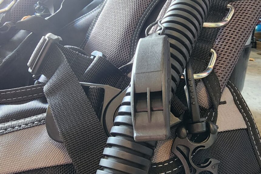 Whistle clipped to the corrugated inflator hose of the SEAC EQ-Pro beside the shoulder D-rings
