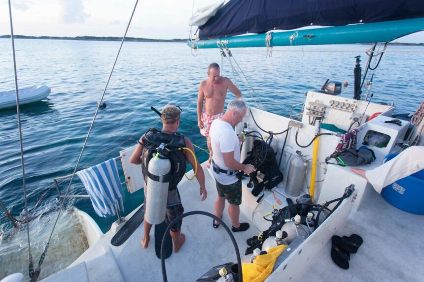 Three divers suiting up with scuba gear on the Cat Ppalu deck