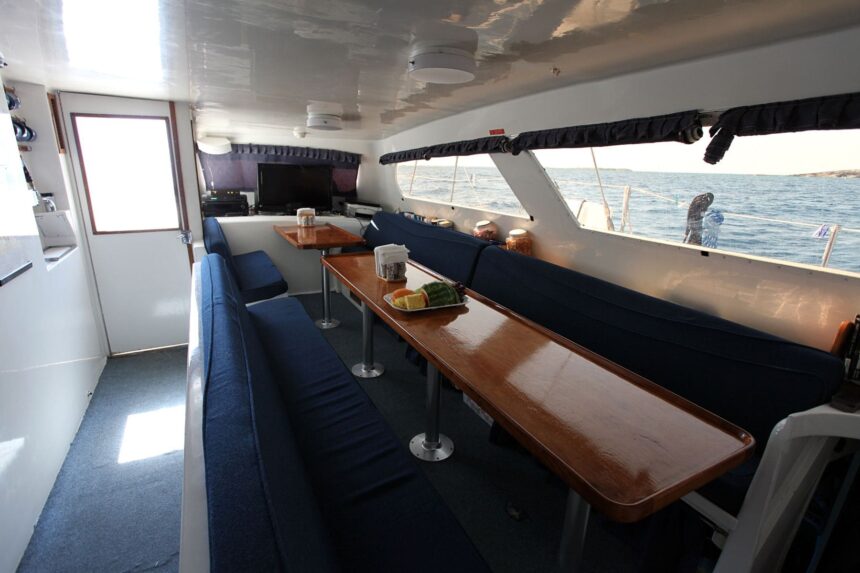 Blue upholstered salon seating and dining table aboard the Cat Ppalu