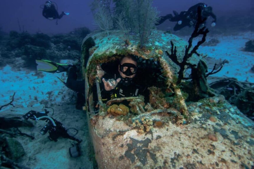 Diver giving a shaka sign inside a sunken plane wreck