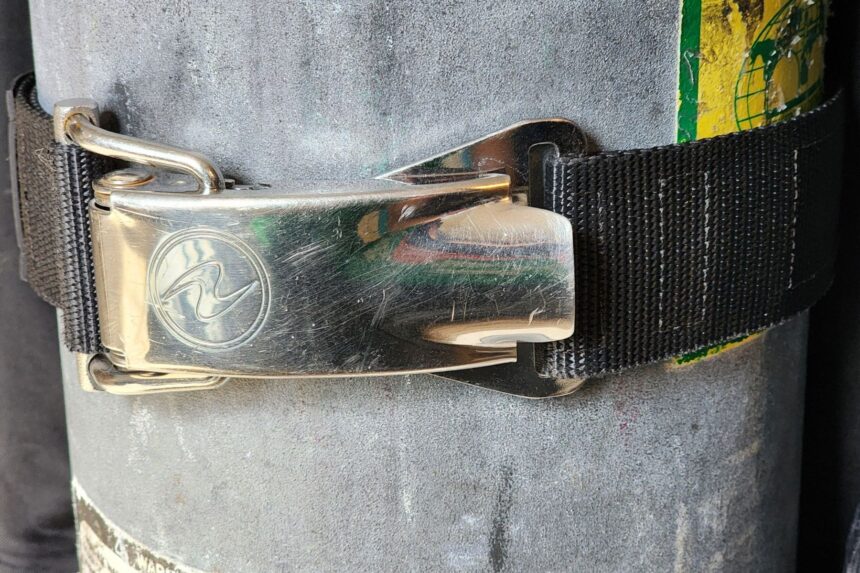 Aqualung stainless cam band buckle with the finger saver lever clamped on a scuba tank