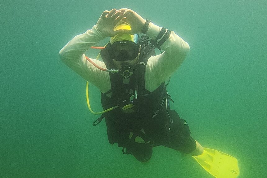DIVEIN tester hovering upright underwater in the Genesis Origin with arms raised overhead