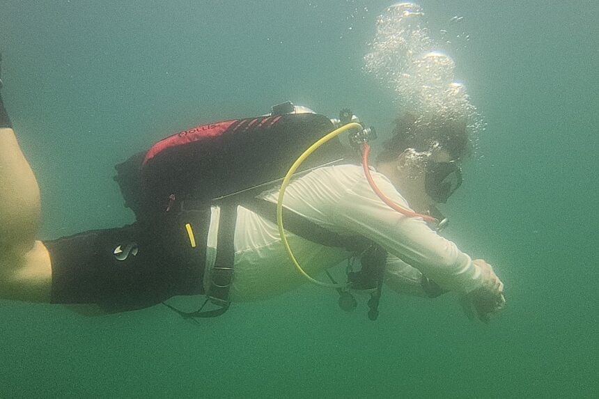 DIVEIN tester exhaling bubbles while finning in the Hollis STS wing during a lake test dive