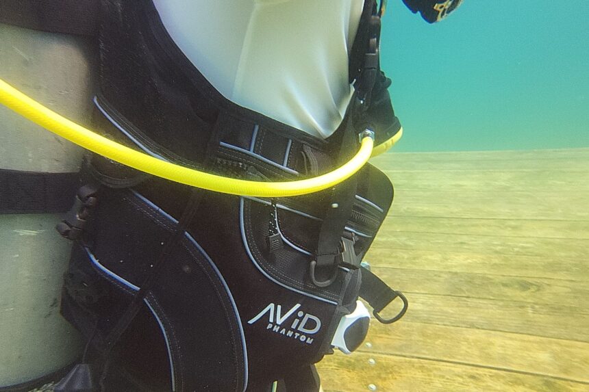 Underwater close-up of the Avid Phantom's yellow inflator hose and weight pocket on our tester