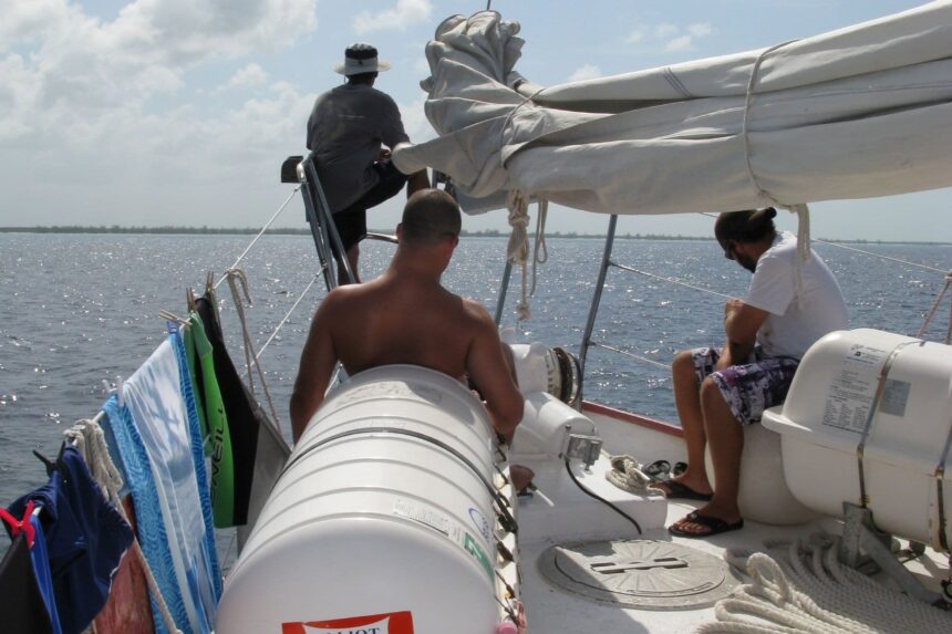 Divers gearing up with scuba tanks aboard the sailboat