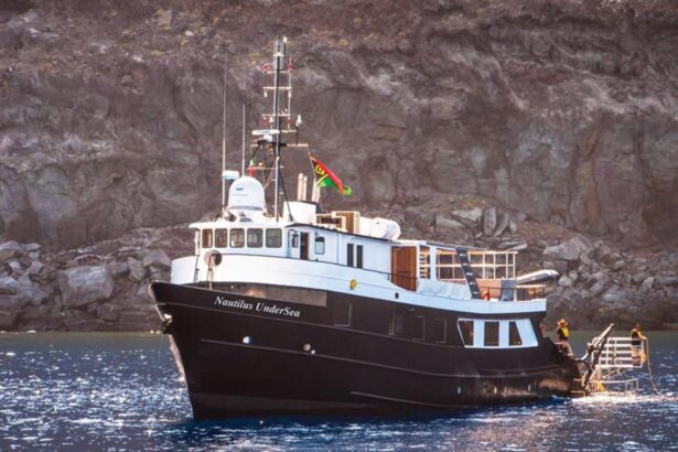 Nautilus UnderSea liveaboard anchored beside a rugged coastline