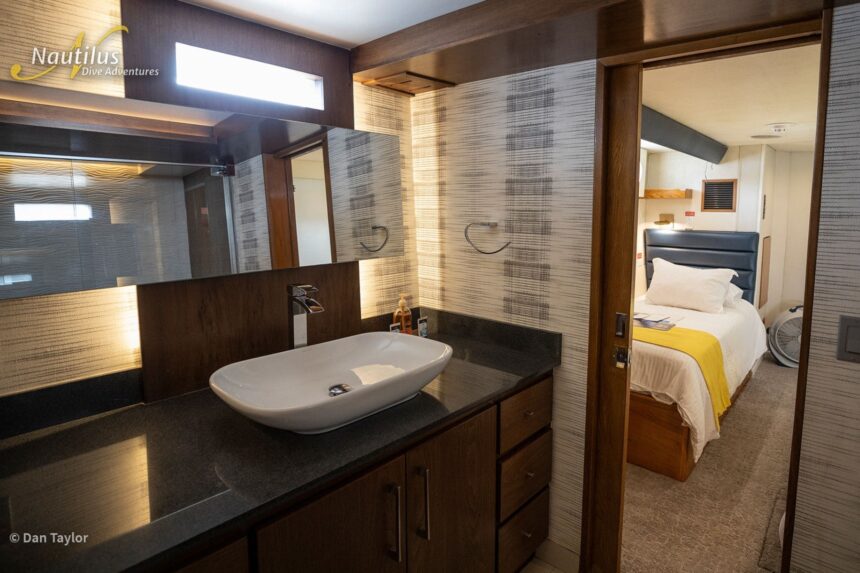 En suite bathroom sink with a view into the adjoining stateroom