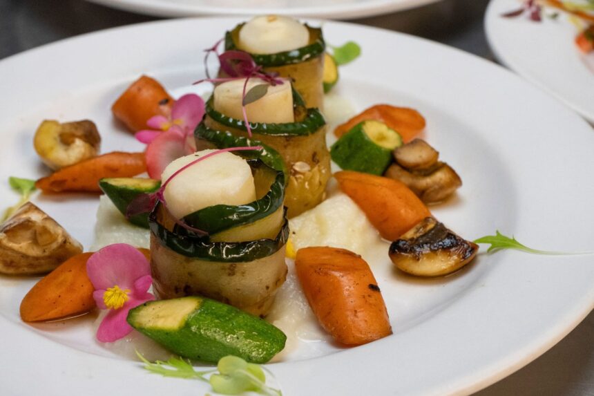 Plated vegetable and scallop appetizer garnished with edible flowers