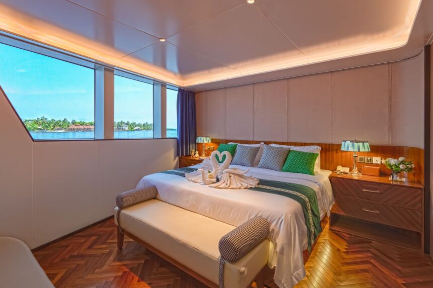 Stateroom bed with ocean view windows and towel swans aboard the M/Y White Pearl