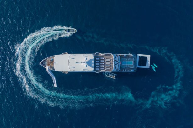 Drone shot looking straight down on the White Pearl with a tender boat circling and carving a wake around it