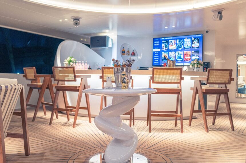 Bar stools and TV screen at the M/Y White Pearl's onboard bar at night